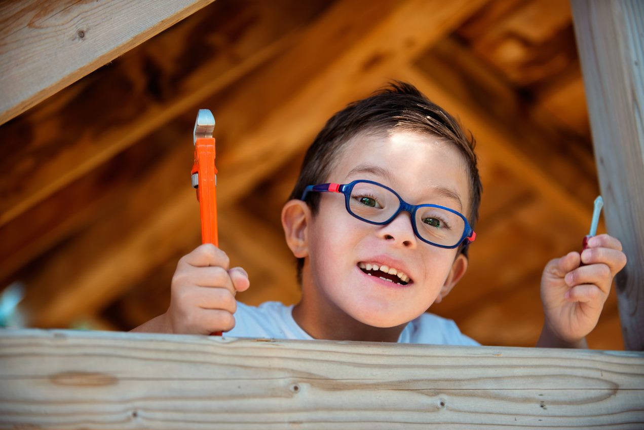 Young boy holding up tools.